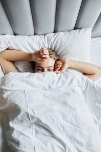 Erschöpfte Frau liegt im Bett – Schlafprobleme im Schichtdienst und Jetlag als Flugbegleiterin